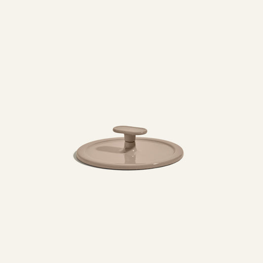 Beige ceramic Grill Press with a round handle, designed for even heat distribution, displayed on a plain light background.
