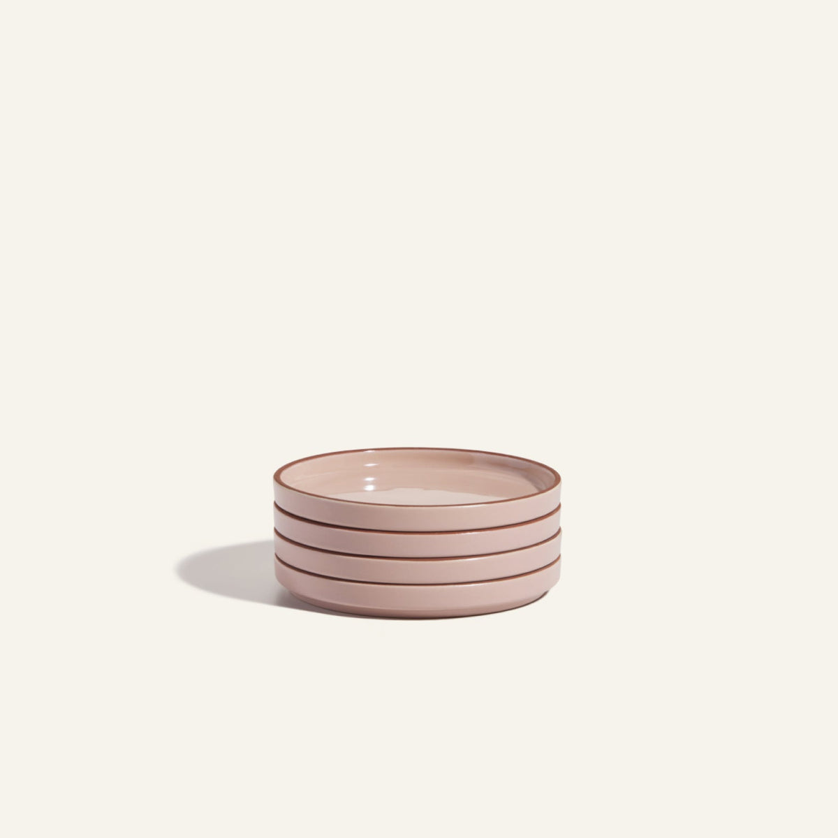 This stack of four round, light pink Dessert Plates with brown rims is scratch resistant and adds elegance to any table setting.