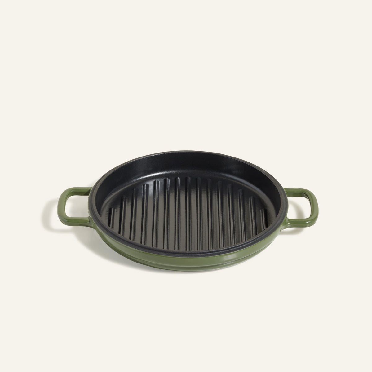 The Cast Iron Hot Grill is a round, green enameled cast iron grill pan with two handles and a ridged black surface—ideal for indoor grilling, shown against a plain light background.
