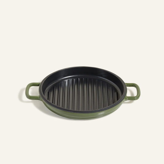 The Cast Iron Hot Grill is a round, green enameled cast iron grill pan with two handles and a ridged black surface—ideal for indoor grilling, shown against a plain light background.