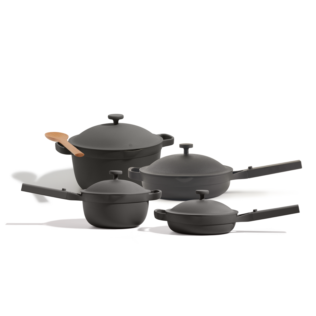 The Cookware Set includes four black nonstick pieces inspired by the Perfect Pot—two saucepans, a deep pan, and a pot—with lids, handles, and a wooden spoon, all arranged on a white background.
