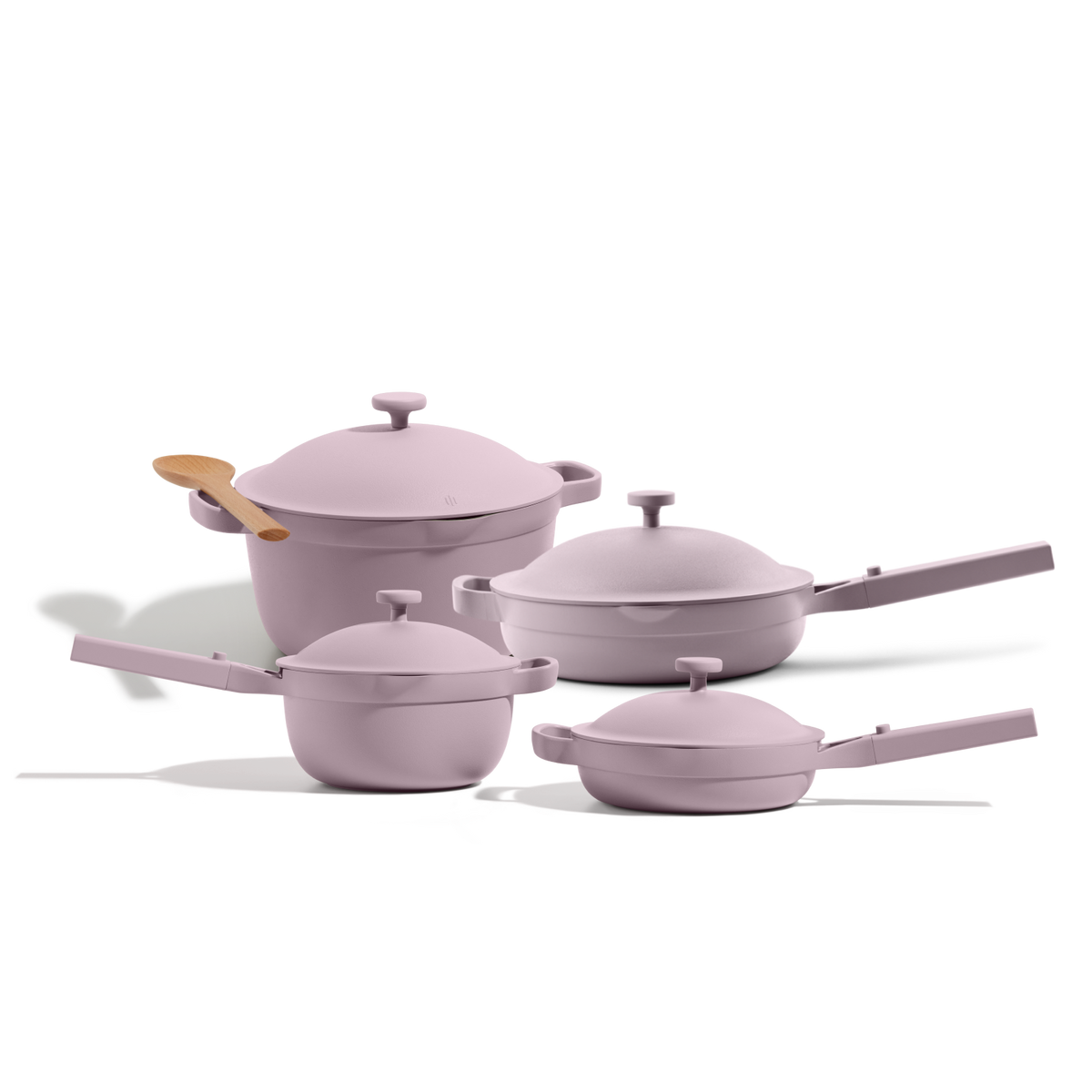 The Cookware Set, featuring four pastel pink pots and pans with matching lids and a wooden spoon inspired by the Perfect Pot, is displayed on a white background.