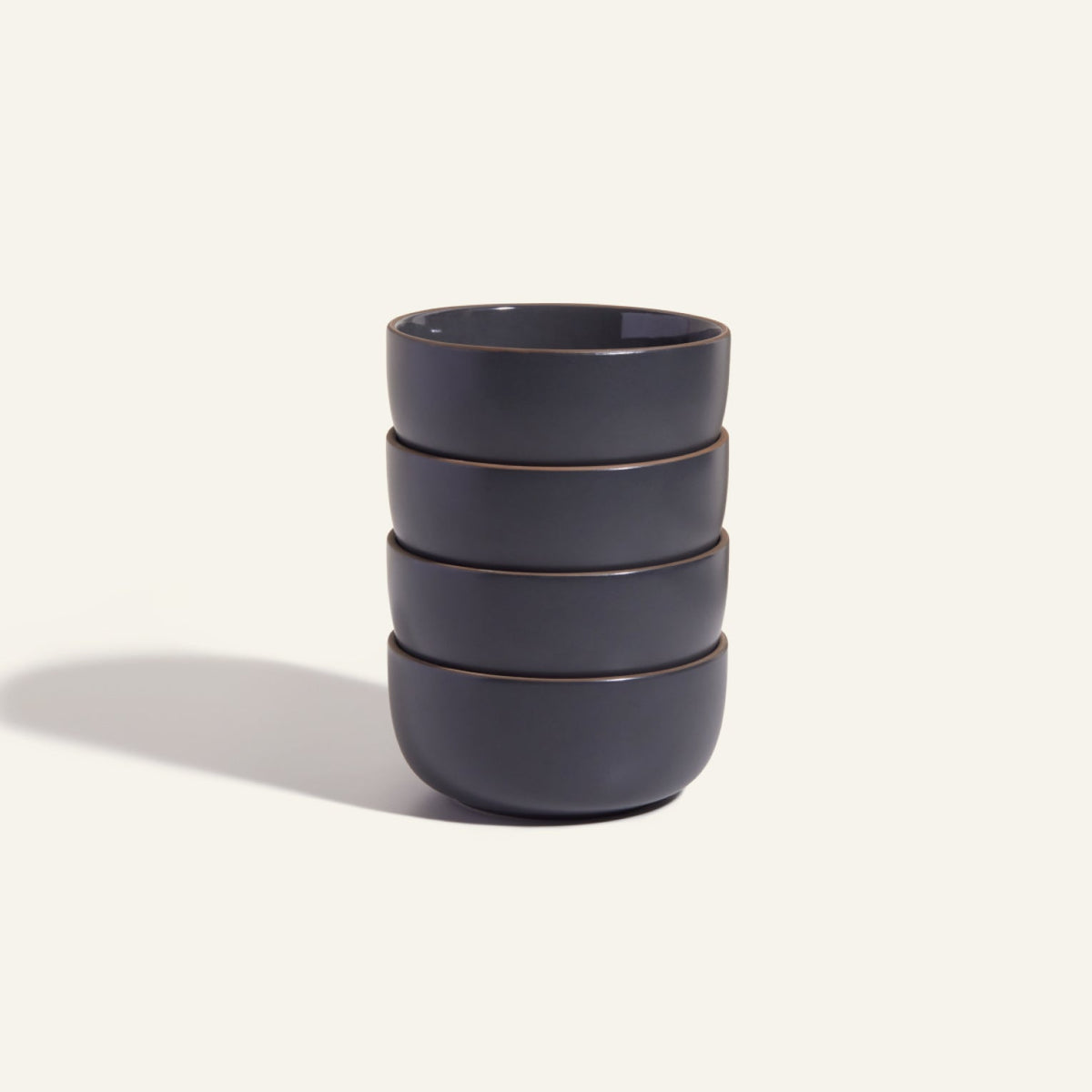 Four dark grey Soup Bowls are stacked vertically against a plain light background, highlighting a modern bowl set ideal for stylish tableware.