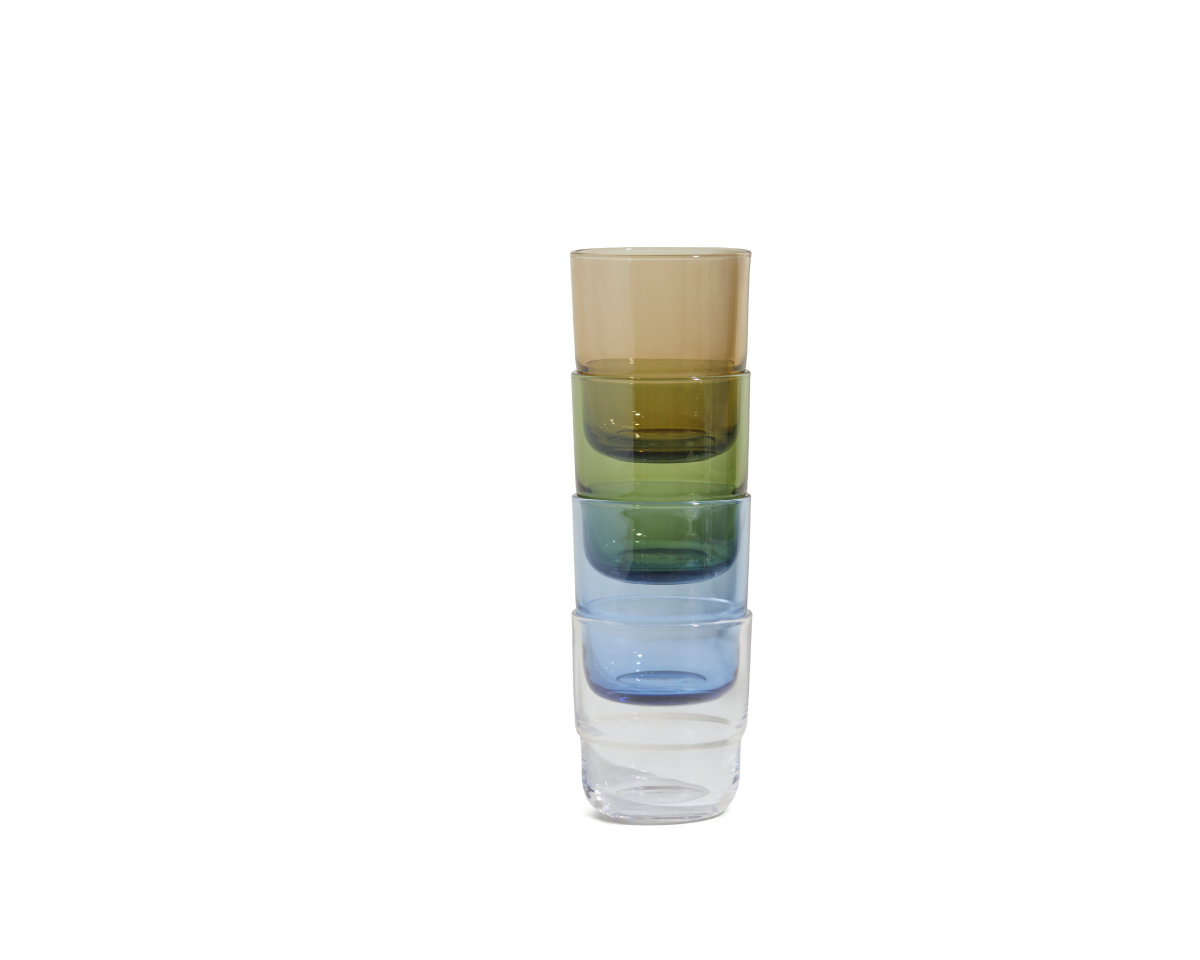 A stack of four Short Night + Day Glasses—brown, green, blue, and clear—made from recycled glass tumblers, arranged vertically on a plain white background.