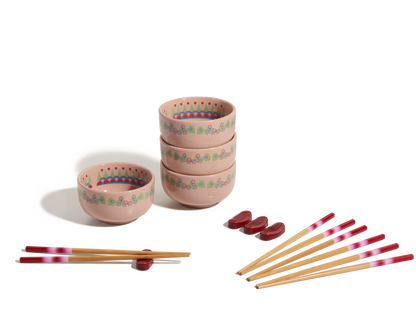 The Rice Bowl Set includes four pink patterned stoneware bowls, matching chopsticks with red and white tips, and red rests—ideal for your Lunar New Year table setting.