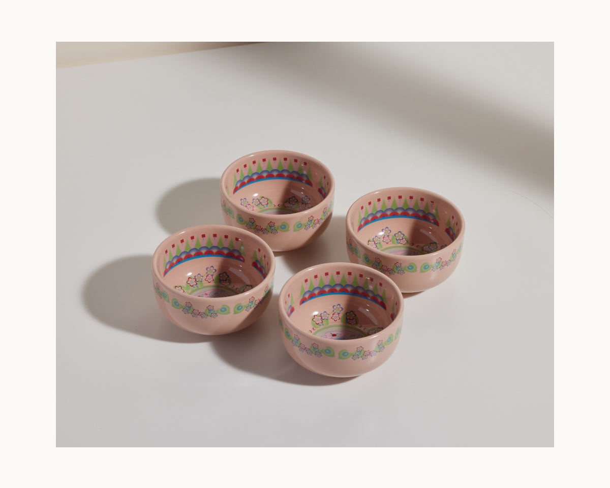 The Rice Bowl Set includes four pink stoneware bowls with decorative patterns and small floral designs, arranged in a square—ideal for Lunar New Year or Year of the Rabbit celebrations.