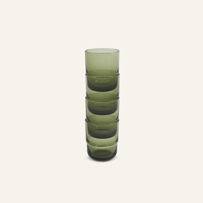 A vertical stack of five Short Night + Day Glasses made from green recycled glass sits on a plain off-white background.