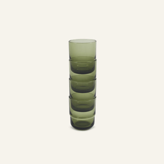 A vertical stack of five Short Night + Day Glasses made from green recycled glass sits on a plain off-white background.