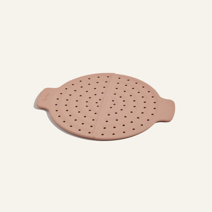 A pink, round silicone steam lid with side handles and evenly spaced holes for splatter prevention—ideal for use with your Fearless Fry pan.