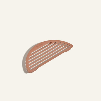 The Fry Deck, a brown, semi-circular slotted trivet with Our Place branding, is perfect for resting your Always Pan or other Our Place cookware and is shown on a plain light background.