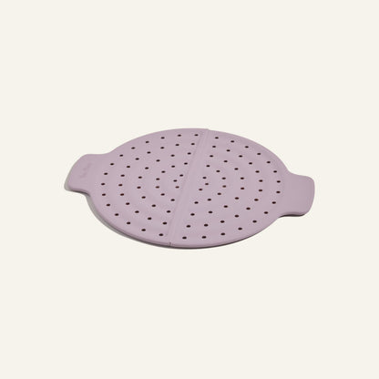 The Fearless Fry is a round, light purple silicone steamer lid with side handles and perforations, designed for the Always Pan to prevent splatter, shown on a plain light background.