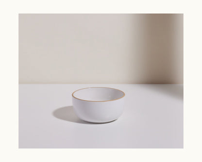 A white Soup Bowl with a thin gold rim, from an elegant ceramic set, is displayed on a white surface with a light beige background.