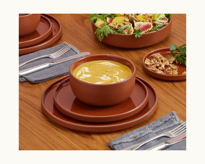 A Soup Bowl from the set rests on matching plates with a salad, walnuts, and napkins with silverware atop a wooden table, highlighting elegant tableware.