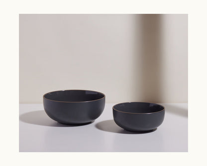 Featuring two matte black Serving Bowls in different sizes, placed side by side on a white surface with a neutral background—ideal as stackable tableware for salads or everyday meals.