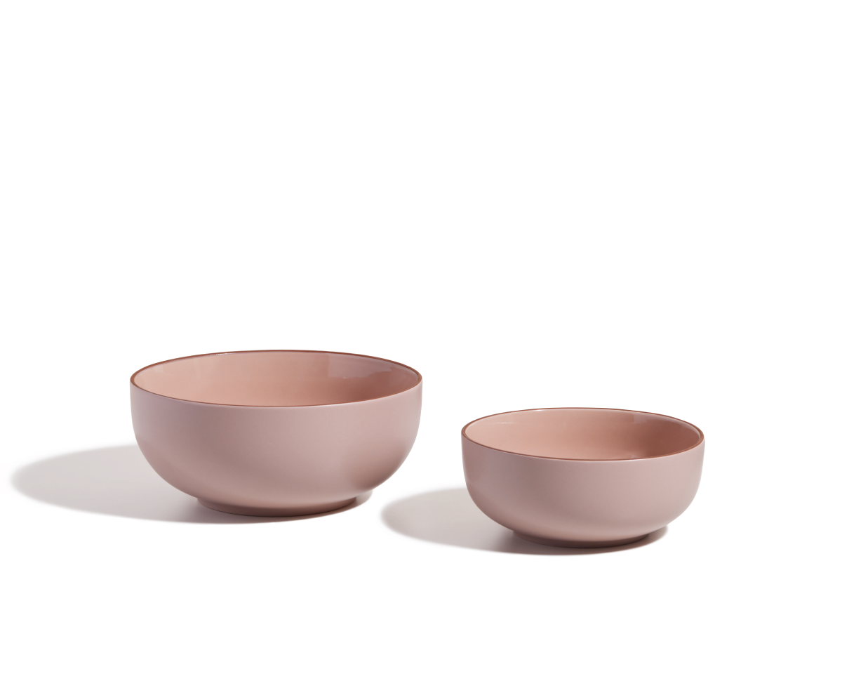 Two stackable Serving Bowls in different sizes, both in pink ceramic, are arranged side by side on a white surface with soft shadows.