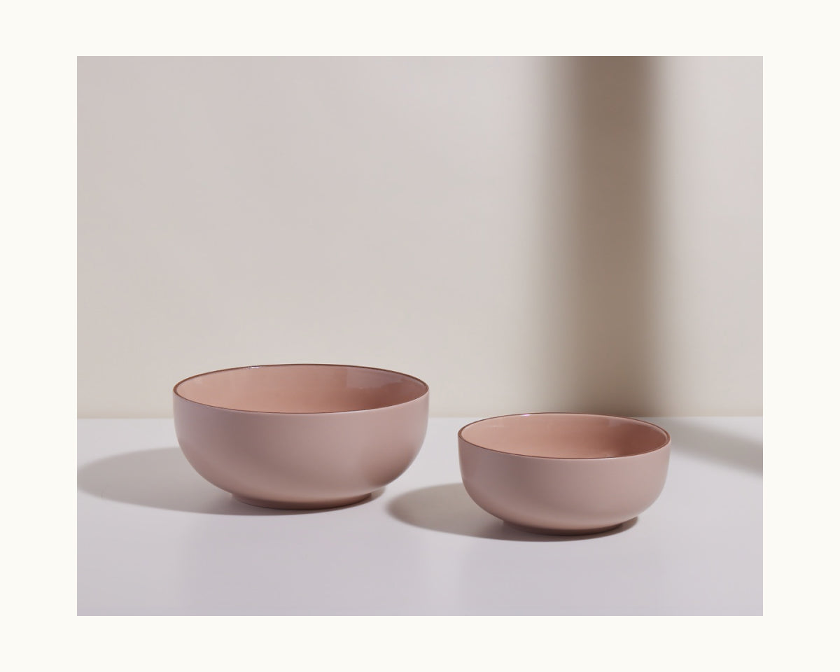 Serving Bowls: A set of two matte pink ceramic bowls in different sizes, stacked stylishly on a white surface against a neutral background—ideal for modern, versatile tableware.
