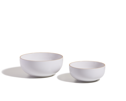 Two white Serving Bowls, one large and one small, with gold rims are shown on a white background with shadows—ideal as elegant, stackable tableware for serving salads.