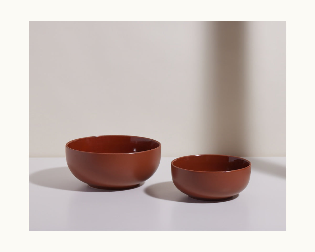 Two brown Serving Bowls of varying sizes are displayed side by side on a white surface with a neutral background.