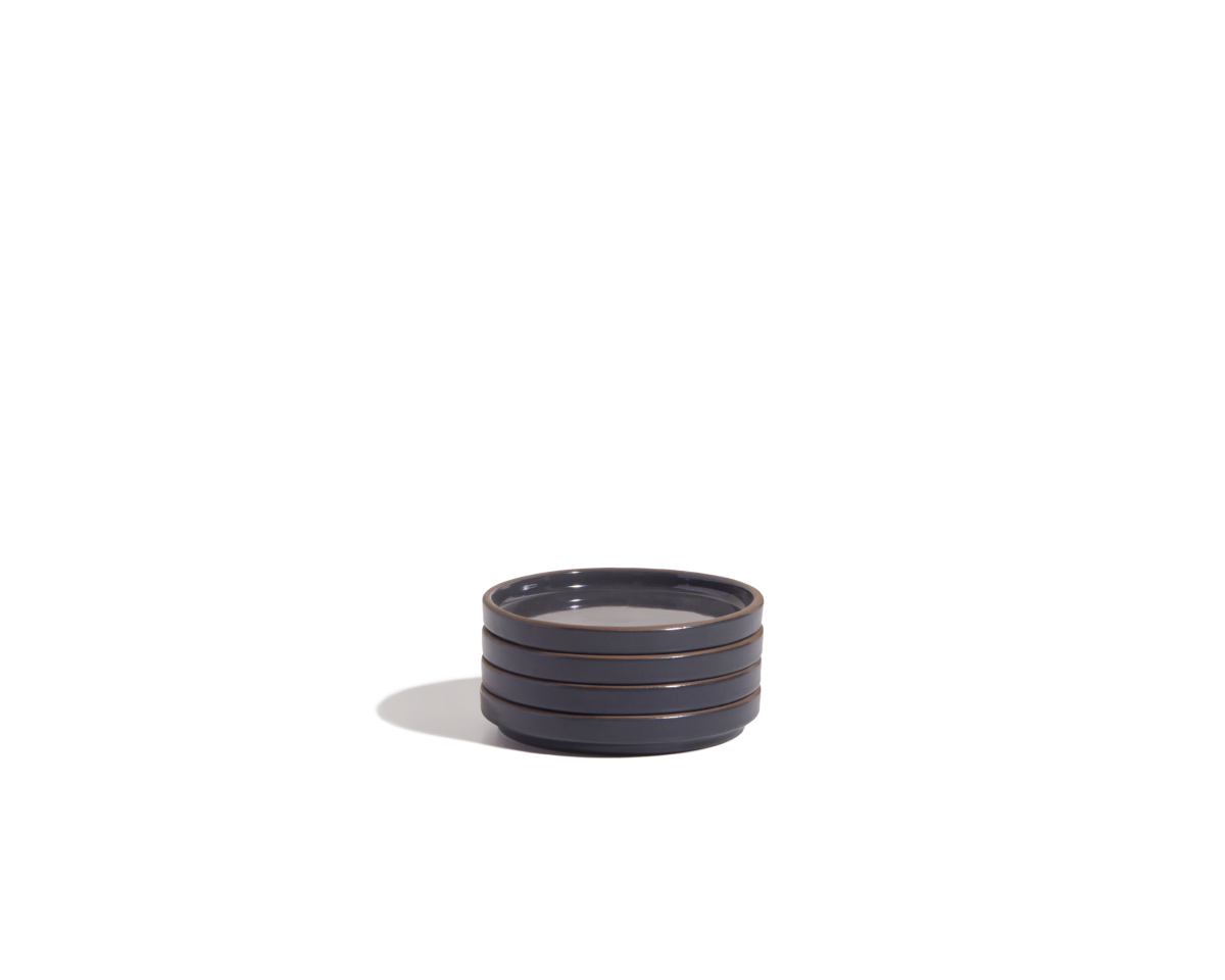 The Tiny Plates are small, round, dark gray ceramic plates with horizontal ridges along the sides, ideal as snack plates and showcased on a plain white background.