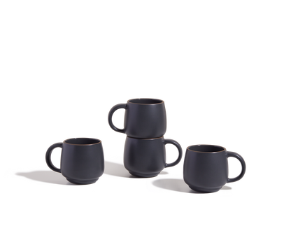 Four Night + Day Mugs in matte black ceramic stoneware, stacked in pairs on a white background—these stackable mugs offer a generous capacity, making them perfect for your favorite drinks.