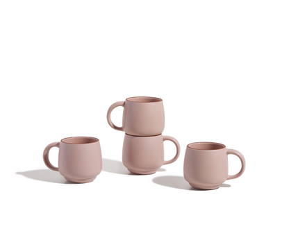 Four Night + Day Mugs in pink ceramic stoneware—two upright, two stacked—are displayed on a white background. These stackable mugs offer ample capacity for enjoying your favorite drinks.