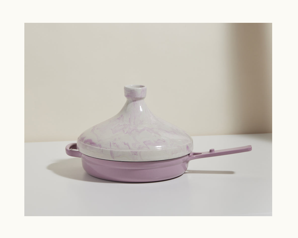 The Tagine, a handcrafted Morocco clay pot in lavender and white marbled tones with a handle, sits on a white surface—ideal for slow cooking and serving as an elegant centerpiece against any neutral background.