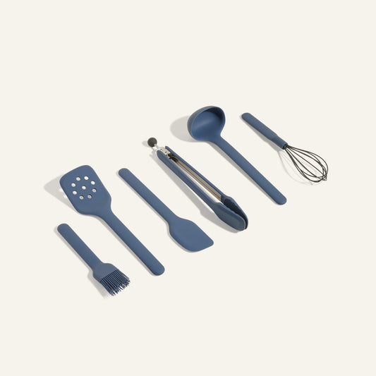 Utensil Essentials features six versatile blue utensils—spatula, slotted spatula, spoon, tongs, whisk, and basting brush—arranged side by side on a light background, ideal for everyday kitchen use.