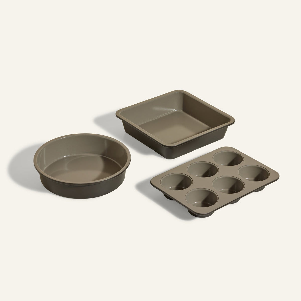 The Wonder Oven Baker’s Kit includes a round cake pan, a square cake pan, and a 6-cup muffin tray—non-toxic and neutral gray—ideal for your Wonder Oven, shown on a light background.