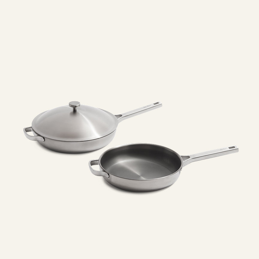 Titanium Pro Always Pan Duo 2.0: two silver-toned stainless steel pans with long handles and helper handles, one with a lid and one without.
