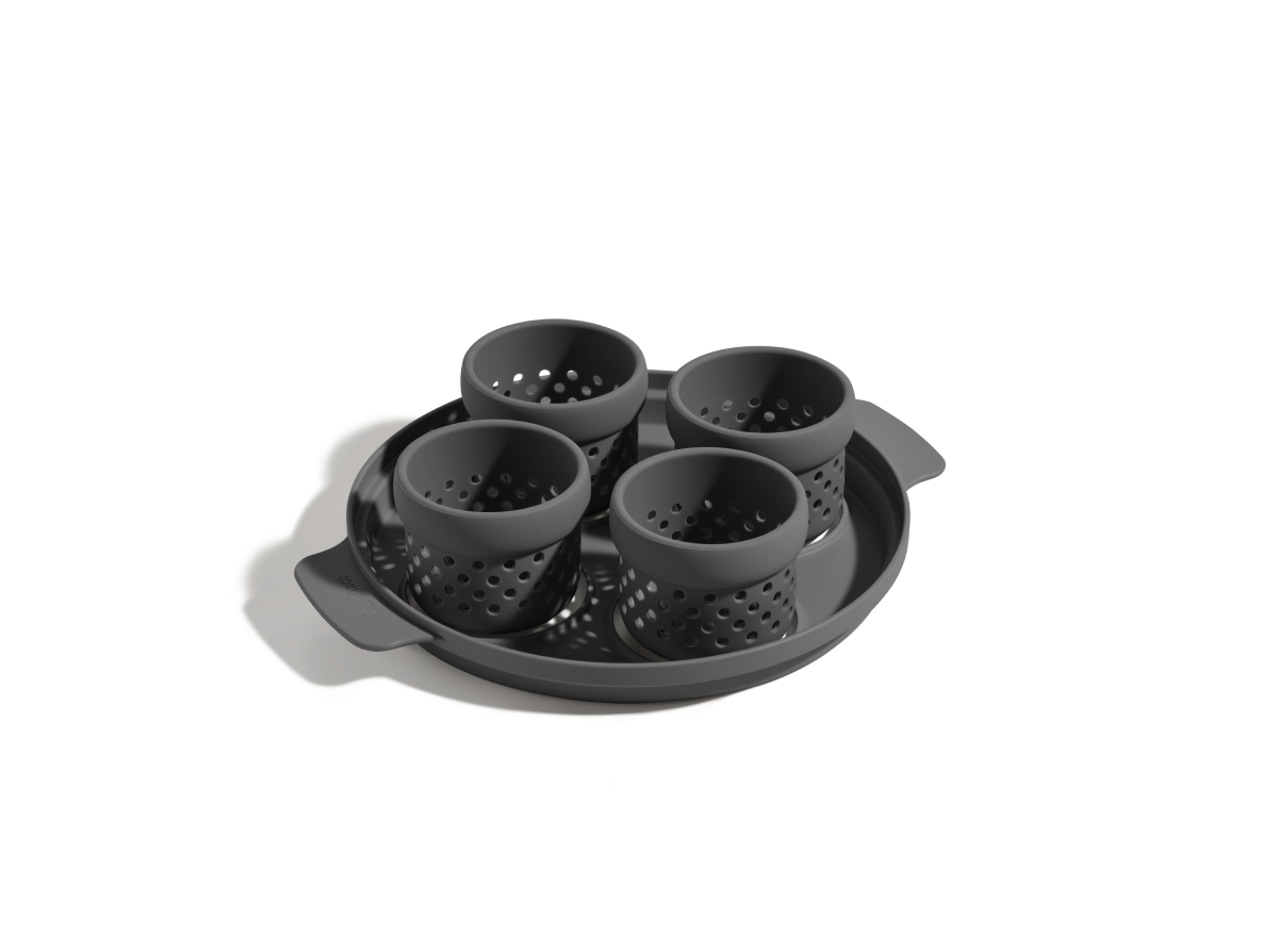 The Egg Poacher is a black silicone set with four perforated cups on a round tray with side handles, ideal for making poached eggs. Shown on a white background.