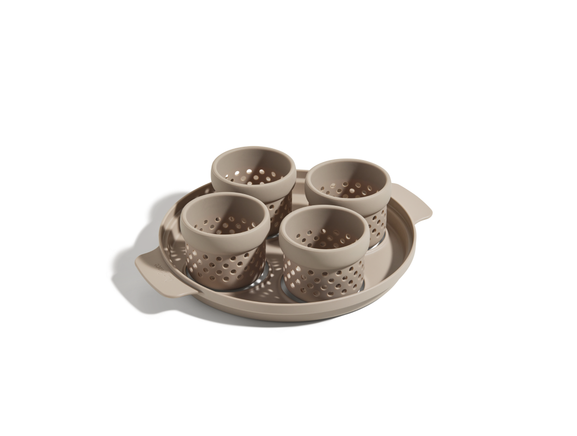 The Egg Poacher is a beige plastic tray with two handles, holding four matching perforated silicone cups, shown on a white background.