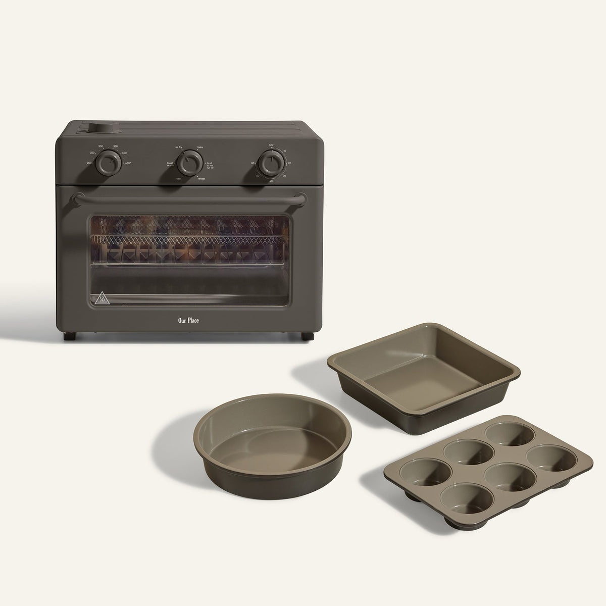 The Large Wonder Oven + Wonder Oven Baker's Kit features three control dials and is shown with a square baking pan, a round cake pan, and a six-cup muffin pan placed in front.
