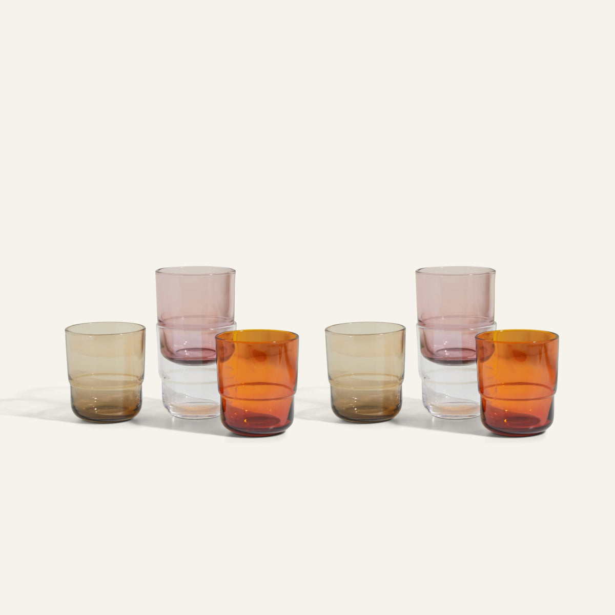 The Short Night + Day Glasses set features six handmade tumblers in amber, pink, and clear shades, arranged in two rows on a light background—perfect for adding vibrant style to any table setting.