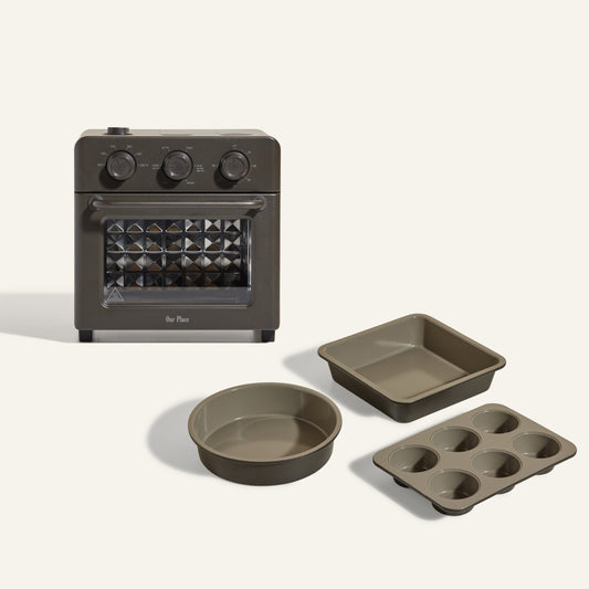 The Wonder Oven + Wonder Oven Baker's Kit features a black countertop oven with three knobs and includes a matching square baking pan, round cake pan, and six-cup muffin tray.