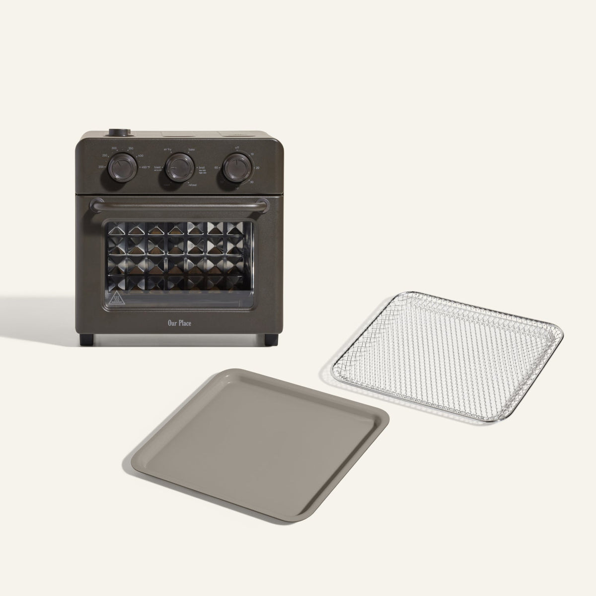The Wonder Oven + Wonder Oven Essentials Kit includes a countertop oven with three control knobs, shown with a metal baking tray and mesh tray, displayed on a plain background.