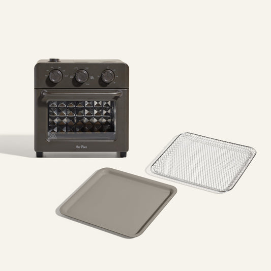 The Wonder Oven + Wonder Oven Essentials Kit includes a countertop oven with three control knobs, shown with a metal baking tray and mesh tray, displayed on a plain background.