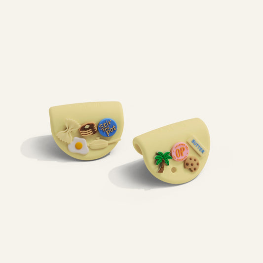 Two yellow silicone grips with decorative elements on a white background