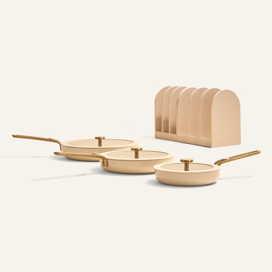 Set of three beige frying pans with gold handles on a white background
