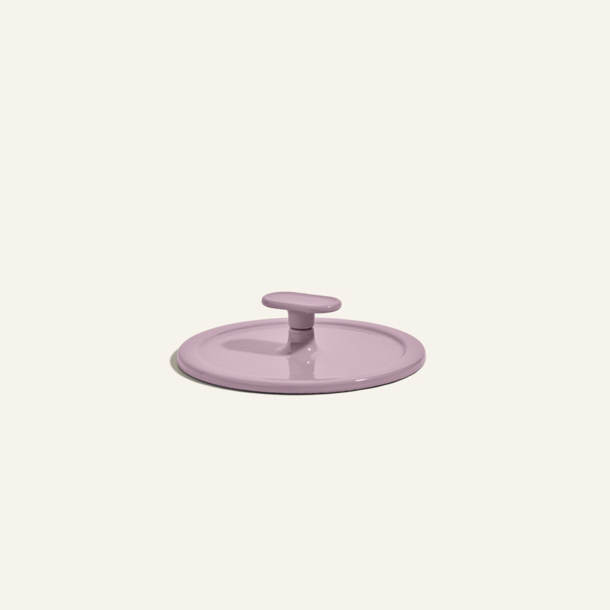 A round, light purple Grill Press with a central handle, crafted from cast iron for even heat distribution, displayed on a plain off-white background.