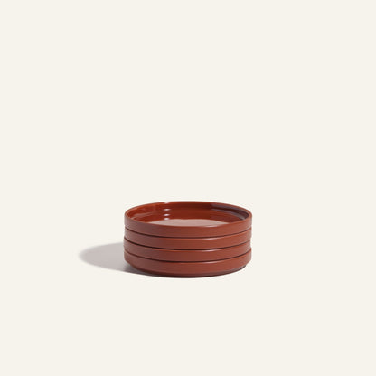 A stack of four round, brown Dessert Plates from an elegant ceramic tableware set is displayed on a plain, light background.