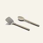 Titanium Pro Utensil Set including a metal spatula with a light-colored handle and a matching light-colored solid spoon.